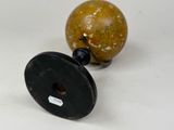 a small wooden object with a black base and a yellow ball
