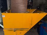 a yellow dumpster sitting in a garage next to a blue machine