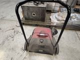 a red and black lawn mower in a warehouse