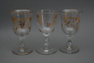 trois verres à pied ornés de motifs dorés, posés sur une table