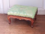 un petit pouf vert posé sur un parquet en bois massif