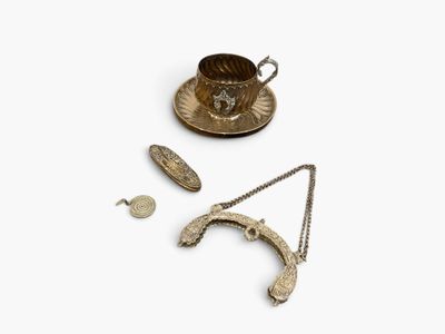 an assortment of silver objects including a tea cup, saucer, and spoon