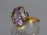 gros plan d'une bague en or avec une pierre violette