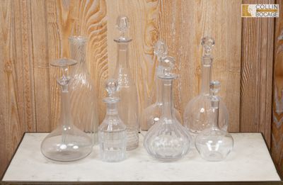 cinq vases en verre posés sur une table devant un mur lambrissé