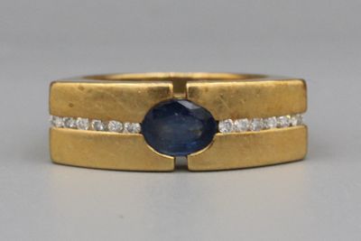 gros plan d'une bague en or avec un saphir et des diamants