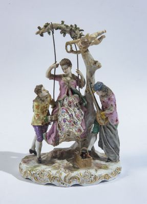 une figurine représentant une femme et deux enfants sur une balançoire