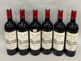 six bottles of red wine are lined up on a table