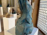 a sculpture of a woman sitting on a pedestal in front of a window