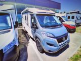 une petite camionnette bleue garée sur un parking, à côté d'autres véhicules