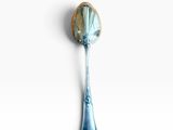 a spoon with a blue handle on a white surface