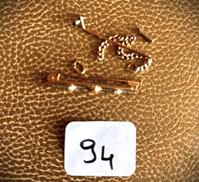 a picture of a gold chain and a gold pin on a brown leather surface