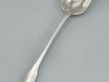 silver plated spoon with a long handle on a gray surface
