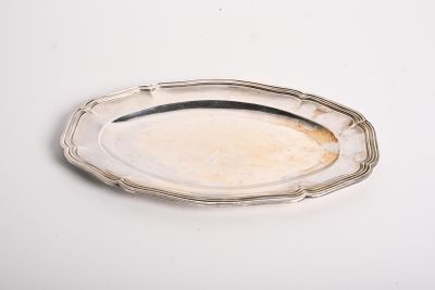 une assiette ancienne en argent sur un fond blanc, bordée d'argent