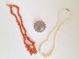 deux colliers et une broche posés sur un fond blanc