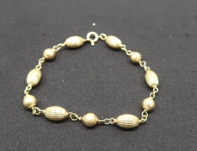a gold bracelet with beads on a black background