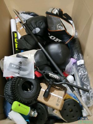 une boîte en carton contenant divers articles, notamment un snowboard, des skis, des bâtons et un casque