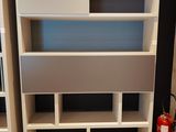 a white book shelf with a fire extinguisor in the corner