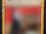 un miroir au cadre doré ouvragé, avec un mur rouge en arrière-plan