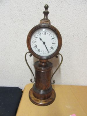 a small clock sitting on top of a table next to a pink flower