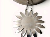 a silver necklace with a flower on it on a white surface