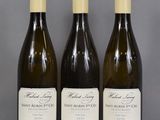 three bottles of wine are lined up on a table