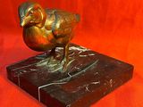 statue en bronze représentant un bélier, posée sur un socle en marbre, sur fond rouge