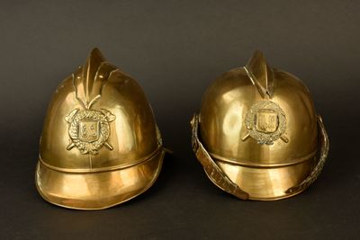 une paire de casques de pompier en laiton sur fond noir