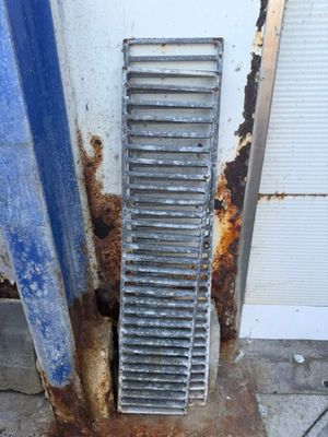 a metal grate on the ground next to a door