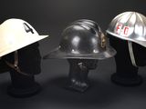 three fire helmets are lined up against a black background