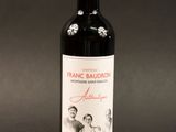 the bottle of red wine is sitting on a black surface