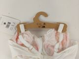 a white bra top with a pink bow on a hanger