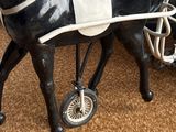 a black horse with a white saddle and a black carriage