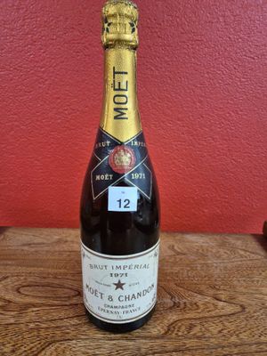 La bouteille de champagne est posée sur la table, devant un mur rouge.
