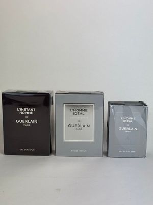 three boxes of perfume sitting next to each other on a white surface