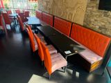 a long table with orange chairs and a black table with a tv on it