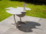 a metal sculpture of a bird on a table in the yard