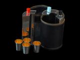 four shot glasses and a bottle of liquor in a holder