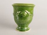 a green vase with a face on it on a table