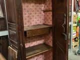 une armoire en bois dont la porte est ouverte, dans une pièce