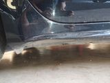 a close up of a car ' s bumper with a person standing in the background