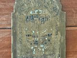 une plaque en laiton fixée sur un mur en bois sur laquelle est inscrit le nom d'un homme