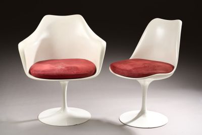 pair of white tulip chairs with red cushions in a dark room