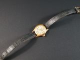 une image représentant une montre-bracelet posée sur une table, sur fond noir