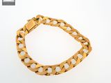 a gold bracelet with a curb link on a white background