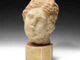 une tête de femme antique en marbre posée sur un socle