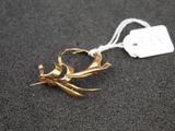 a gold bird brooch with a tag attached to it
