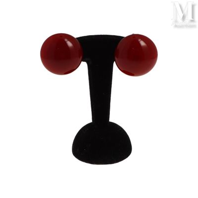 a close up of a pair of red earrings on a black stand