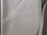 a white purse sitting on top of a gray chair