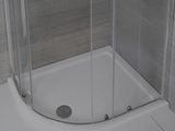 une douche avec une porte vitrée, située dans un coin de la pièce