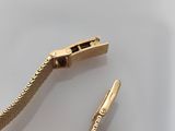 two pieces of gold colored metal with a clasp on a white surface